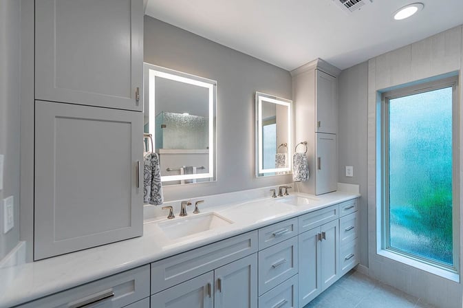 A remodeled bathroom in a Houston, Texas, home with Jack-and-Jill vanities, built-in storage cabinets, and porcelain counter