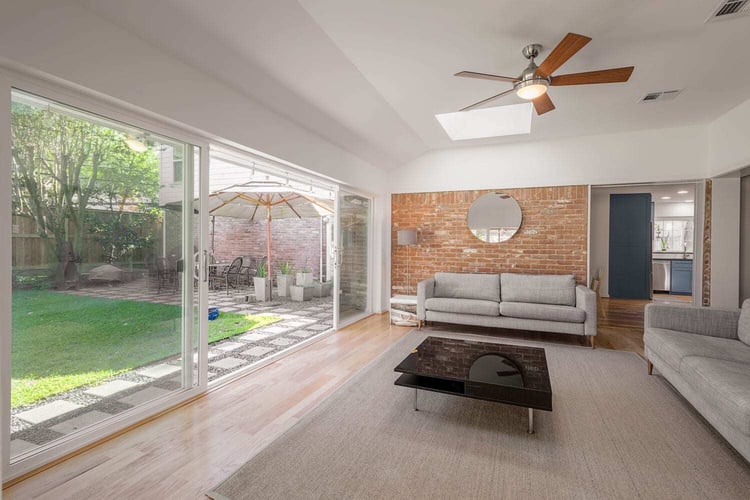 All Star Construction sunroom addition on Old Oaks Drive in Houston with sliding glass doors, a skylight, and an exposed brick wall.